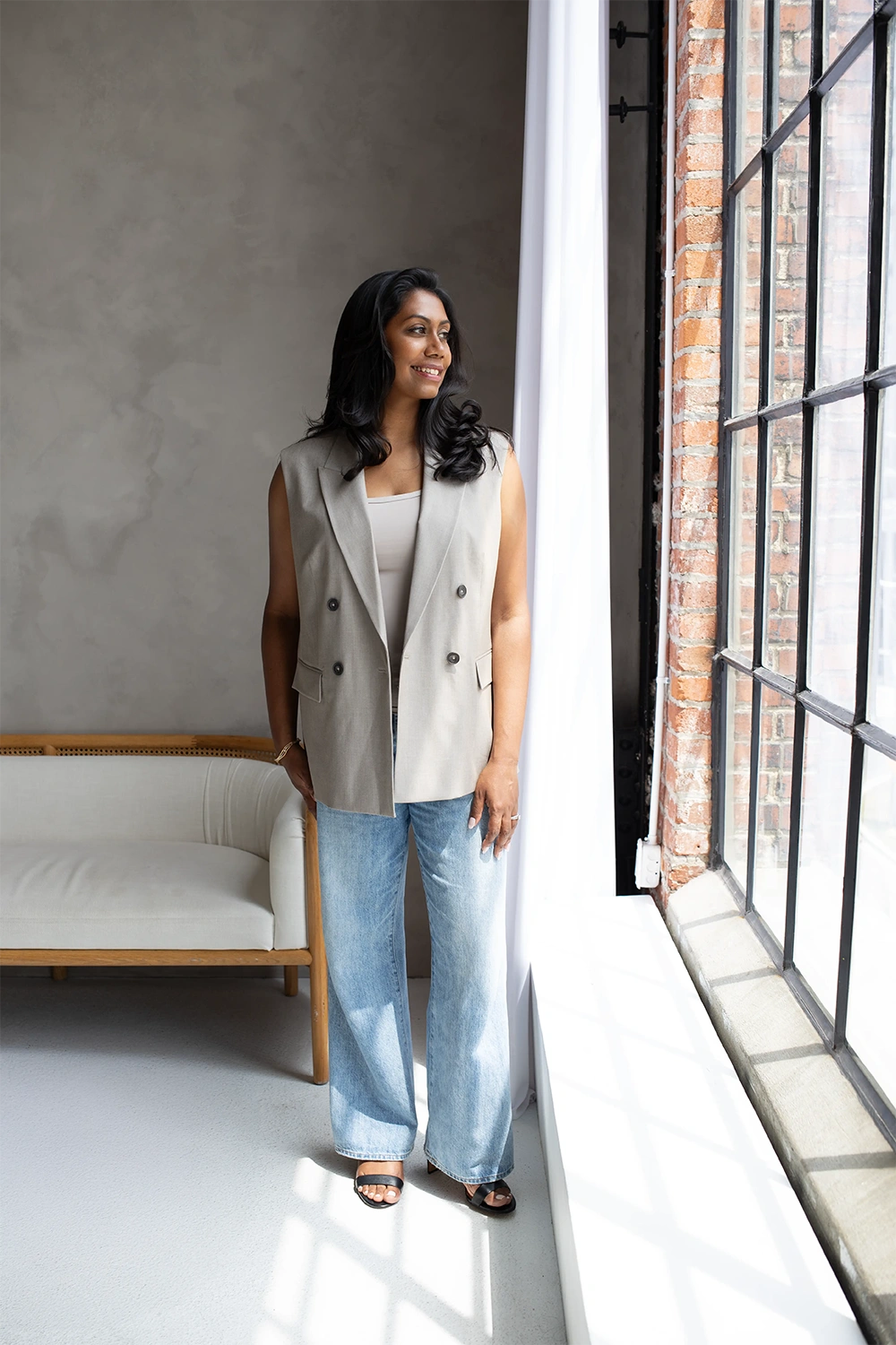 Editorial brand portrait of a practitioner in a tailored vest and denim