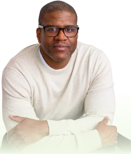 Man wearing glasses and a light beige sweater with arms crossed, looking at the camera.