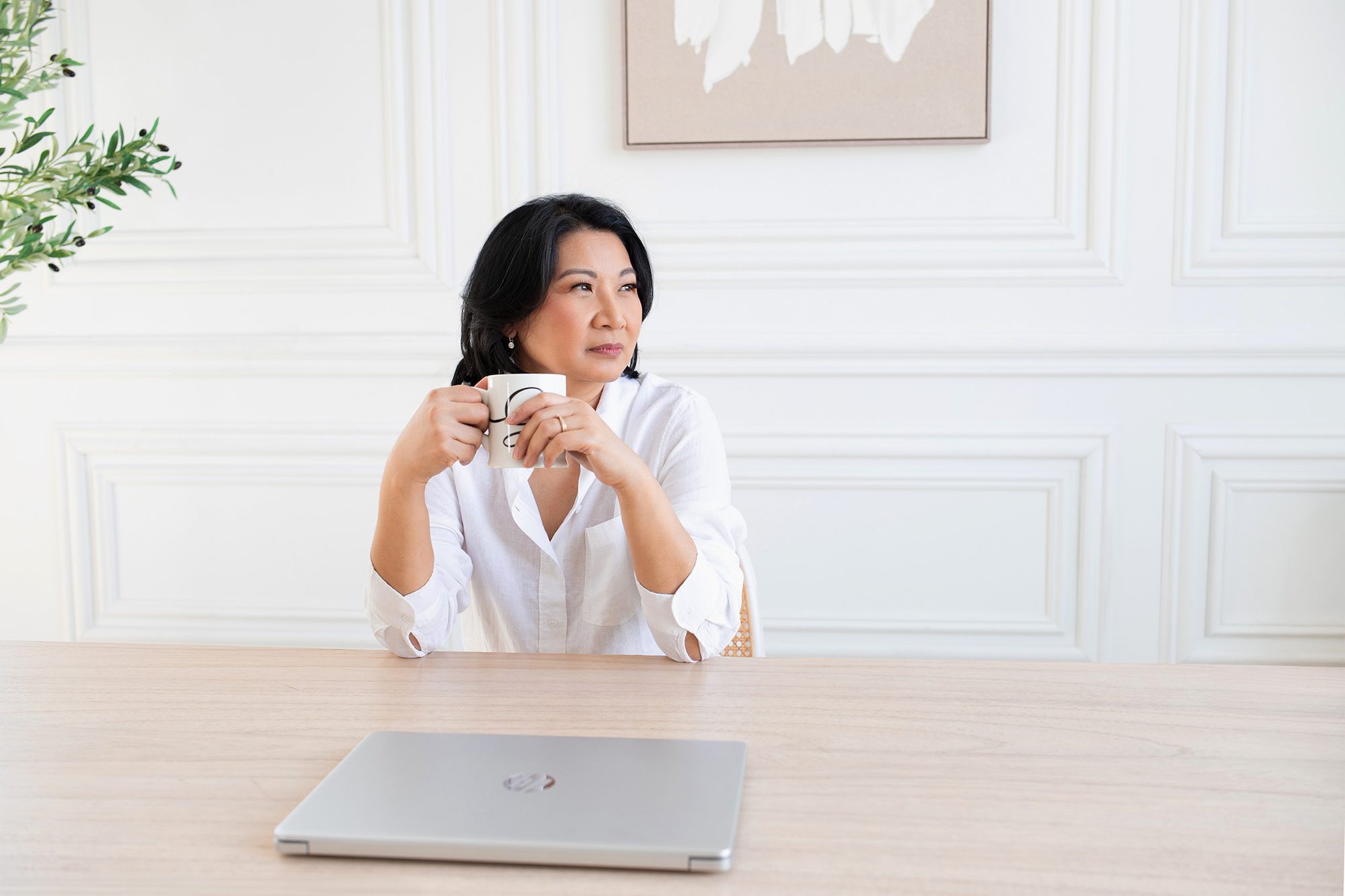 Practitioner at her desk with a coffee, candid brand photography